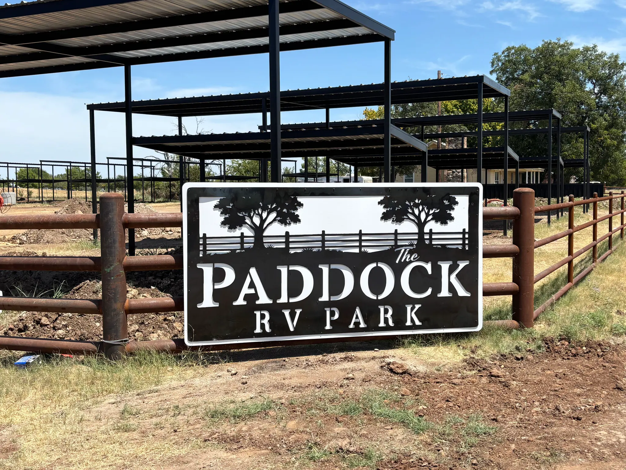 The Paddock RV Park sign mounted on the pipe fence at the entrance on CR 292